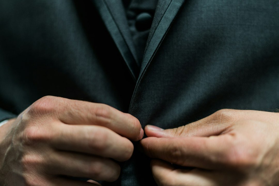 Gömleğinin düğmesini ilikleyen kişinin elleri; ince motor beceriyi anlatan temsili fotoğraf